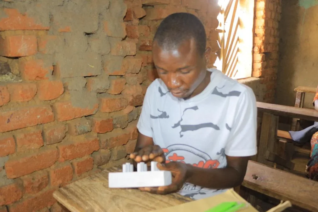 A visually impaired young man practices with a Braille board
